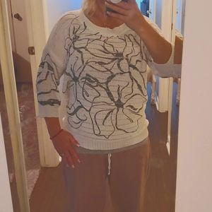 White sweater with Black flower design.